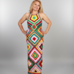 Model poseert in een kleurrijke gehaakte maxi-jurk met vrolijke tinten en bohemian uitstraling, perfect voor stranddagen of zomerse avonden.